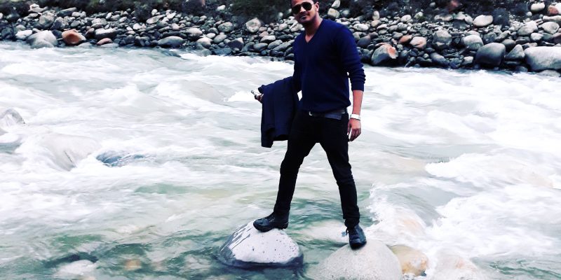 Young man in river & hilly area – free photo